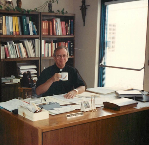 Monsignor Jack M. Dinkins sitting in his office drinking coffee.